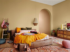 Warm deep tan with boho bed and colourful rugs orange pillow and wooden floor